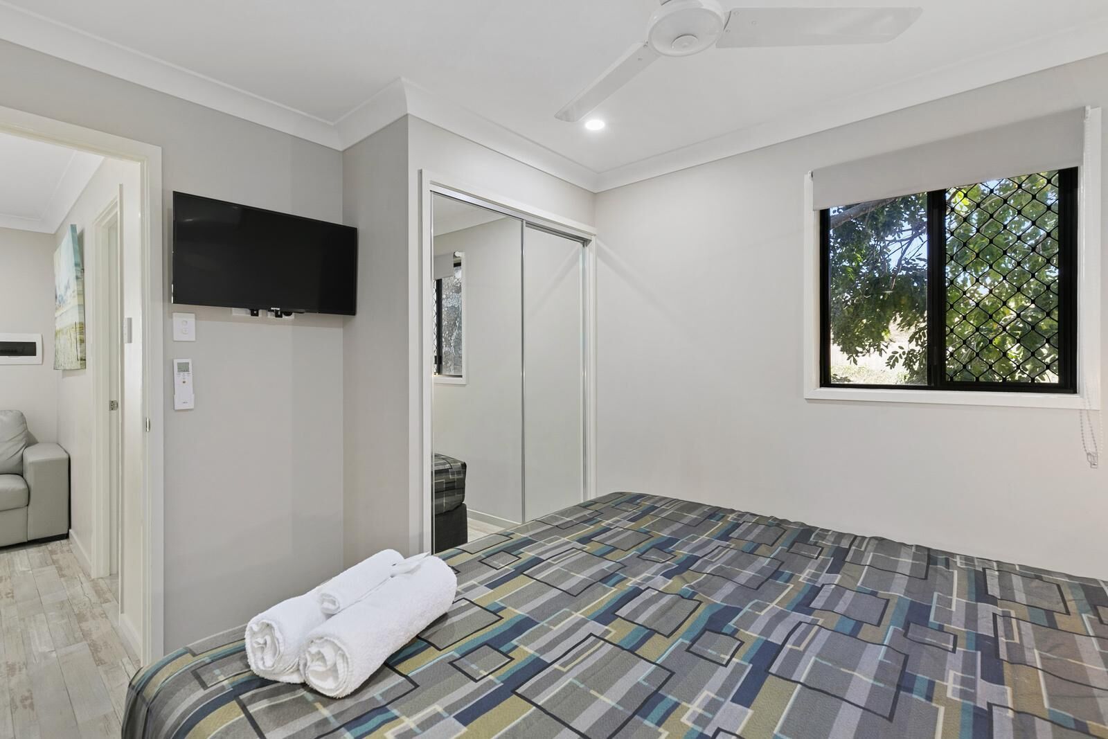 A bedroom with a bed, a TV, a wardrobe, a window, and a door.