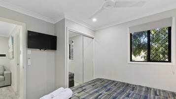 A bedroom with a bed, a TV, a wardrobe, a window, and a door.