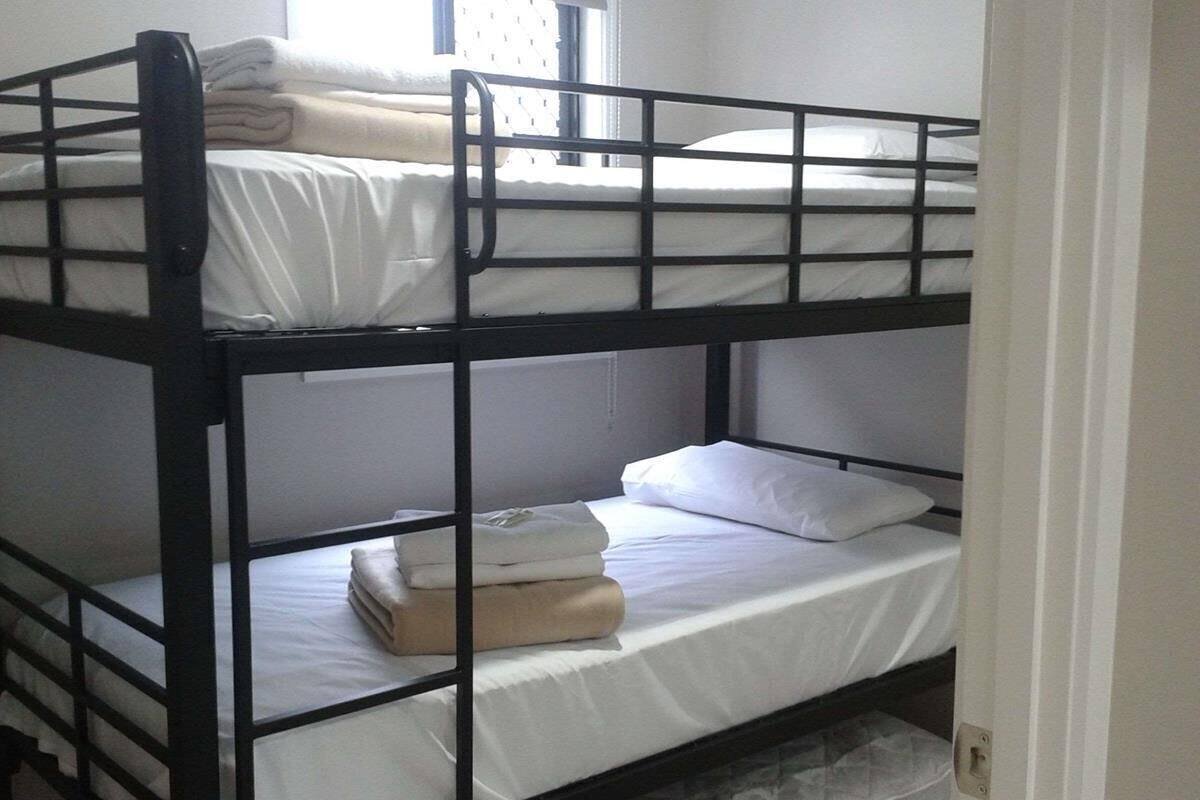 A bunk bed room with white bedding and a window.
