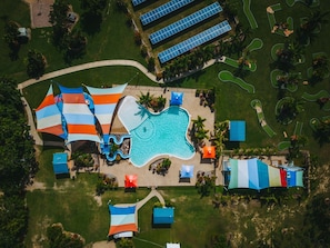 Vue aérienne d’un complexe hôtelier doté d’une piscine, de toboggans aquatiques et de panneaux solaires.