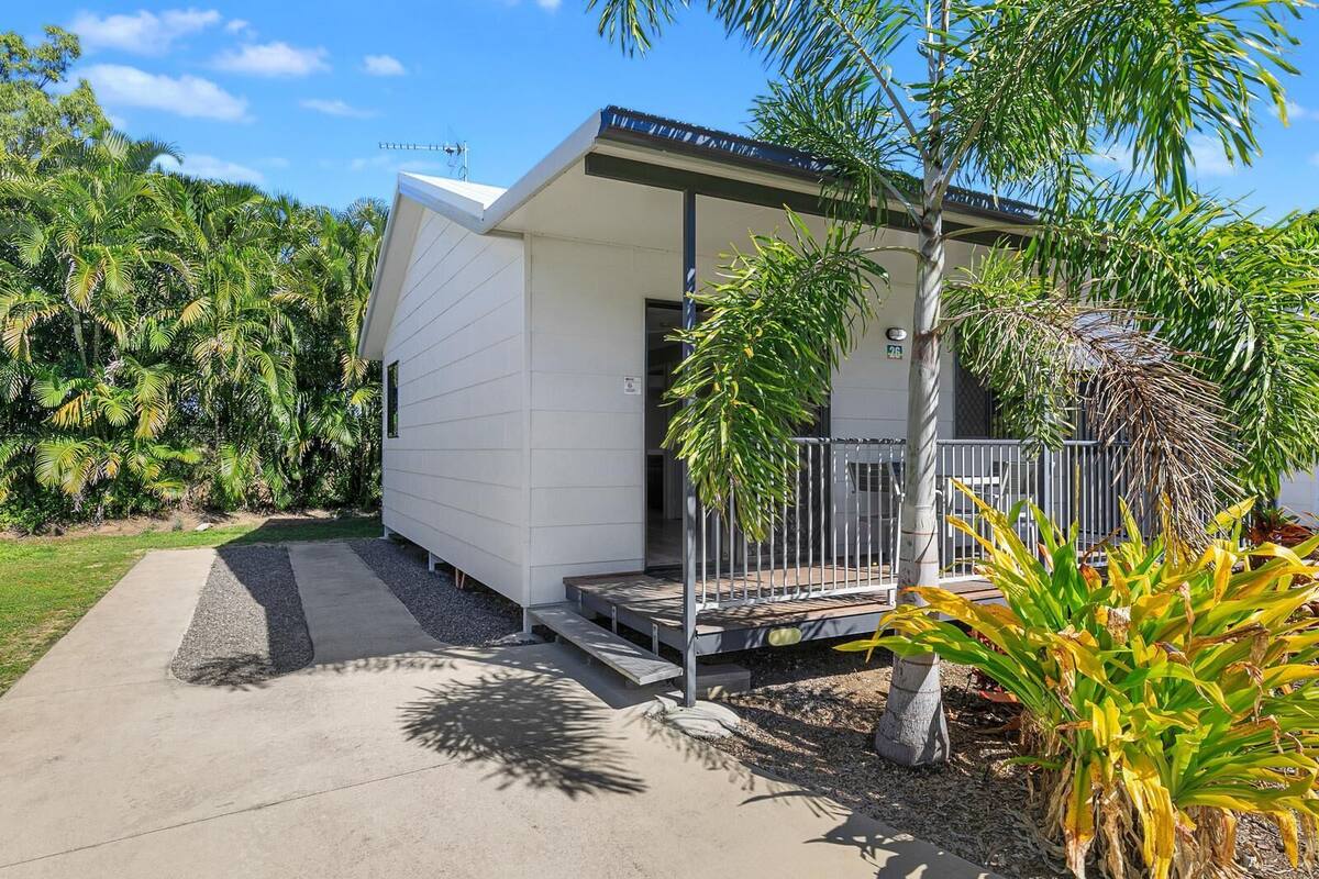 A modern house with a covered porch, surrounded by lush greenery.