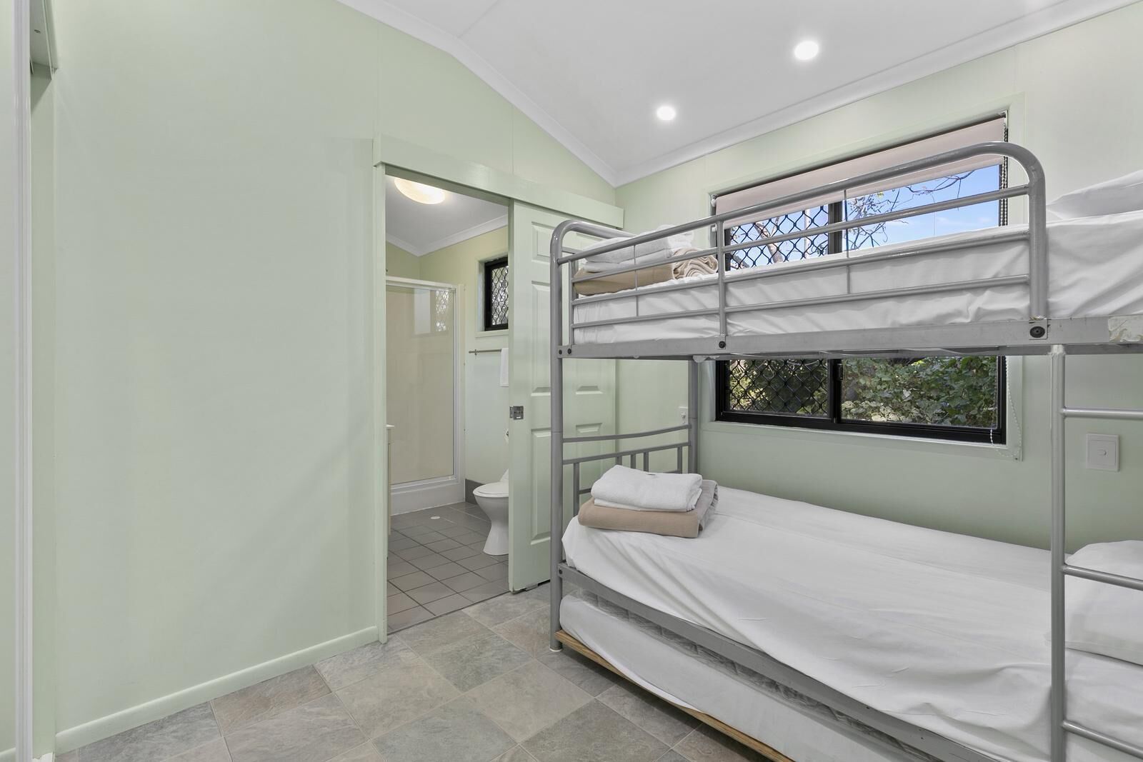 A bunk bed room with a bathroom visible through an open door.