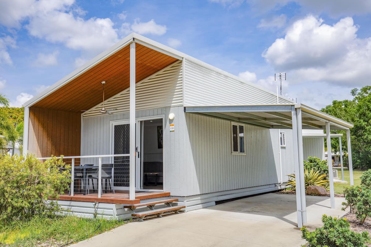 A single-story house with a covered porch, a wooden deck, and a small outdoor seating area.