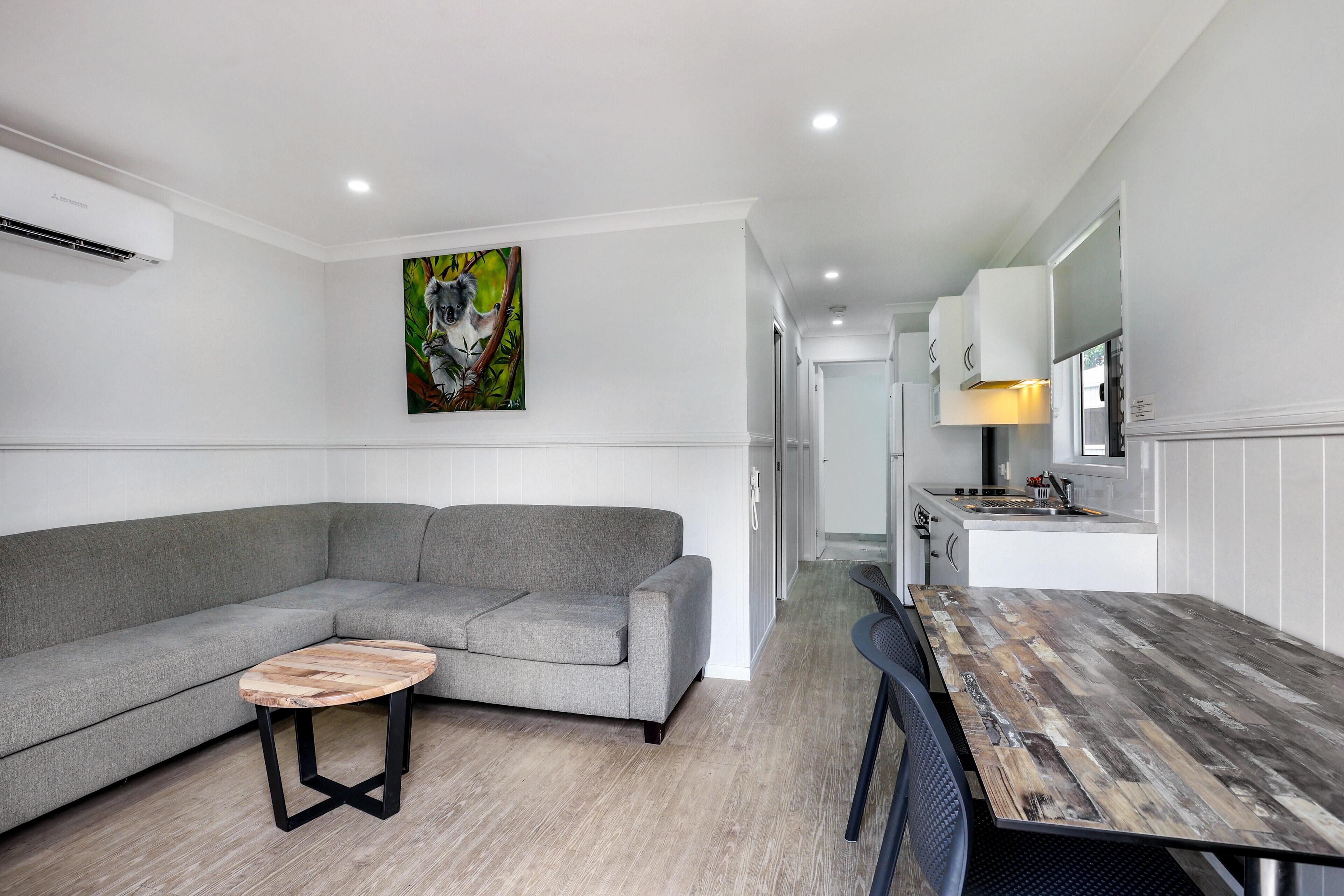 Una sala de estar moderna con un sofá gris, una mesa de centro de madera y un comedor con una mesa de madera rústica.