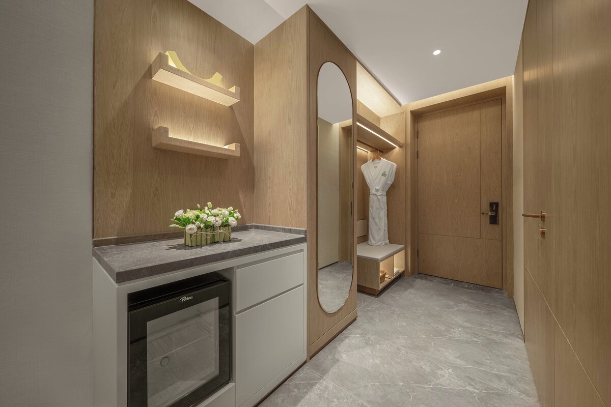 A modern bathroom with a marble countertop, a built-in sink, a mirror, and a wooden vanity.