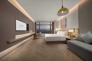 A modern hotel room with a bed, a desk, a sofa, and a large window offering a city view. - Holiday Inn Fu'An by IHG (Ningde)