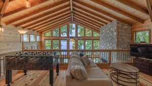 A cozy room with a wooden ceiling, stone wall, and large windows. - Aspen Shores by Innsbrook Vacations! (Innsbrook)