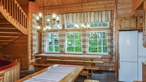 A wooden cabin interior with a dining table, benches, a chandelier, a refrigerator, and a staircase. - Porukka 2 by Interhome (Kittilä)
