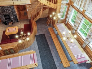 A wooden interior with a staircase, seating areas, and a fireplace.