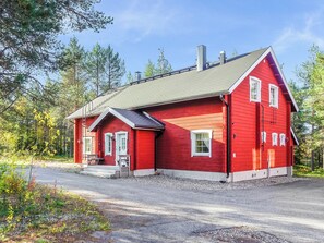 Una casa de madera roja con techo inclinado, un porche delantero y una chimenea.
