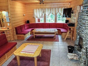 Et interiør af en hytte med en rød sofa, et træbord og en stenspir.