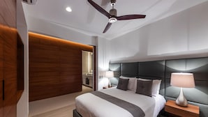 Une chambre à coucher moderne avec un grand lit, un ventilateur de plafond et un mur d’accent en bois.