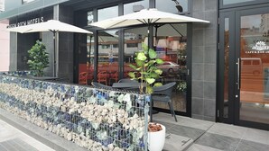 Una entrada de hotel moderna con asientos al aire libre y una pared decorativa de roca.