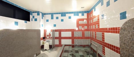 A bathroom with a tiled floor, a glass shower enclosure, and a sink area.