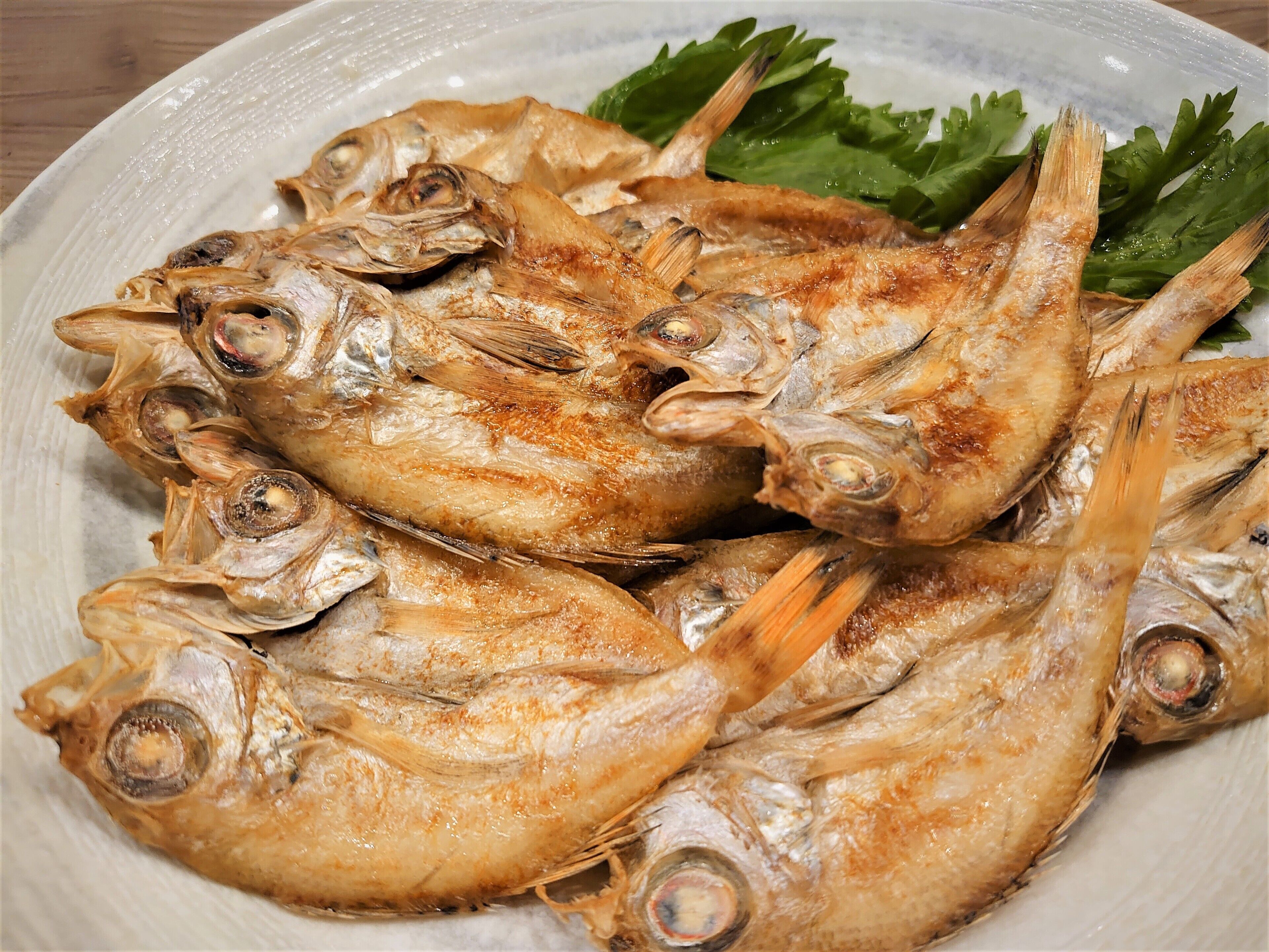 Une assiette de poisson grillé, garnie de feuilles vertes.