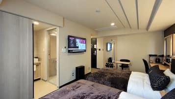 Une chambre d’hôtel avec deux lits, un téléviseur fixé au mur, un bureau avec une chaise et une petite table avec une machine à café.