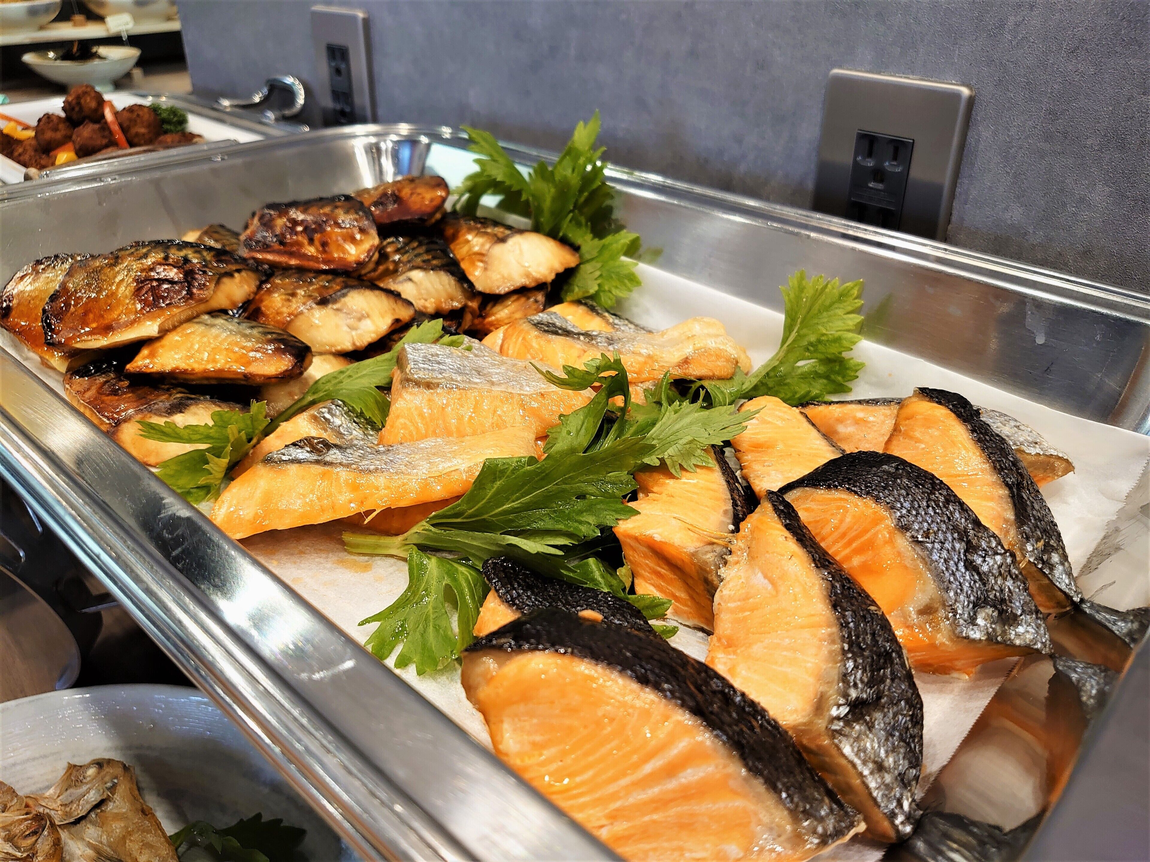 A buffet with grilled fish and vegetables.