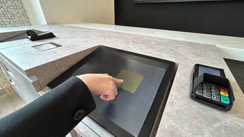Un terminal de pago digital y una tableta sobre un mostrador.