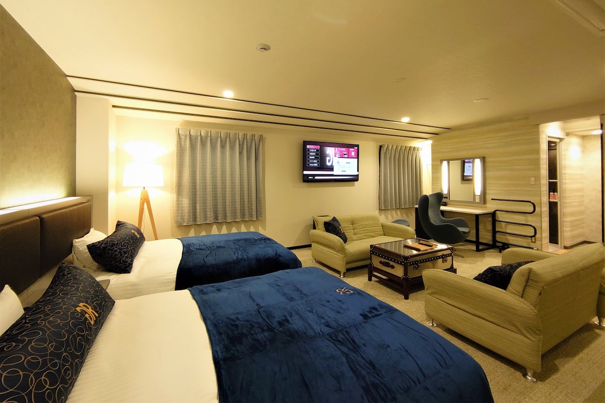 Een hotelkamer met twee bedden, een bureau, een stoel, een televisie en een kledingkast.