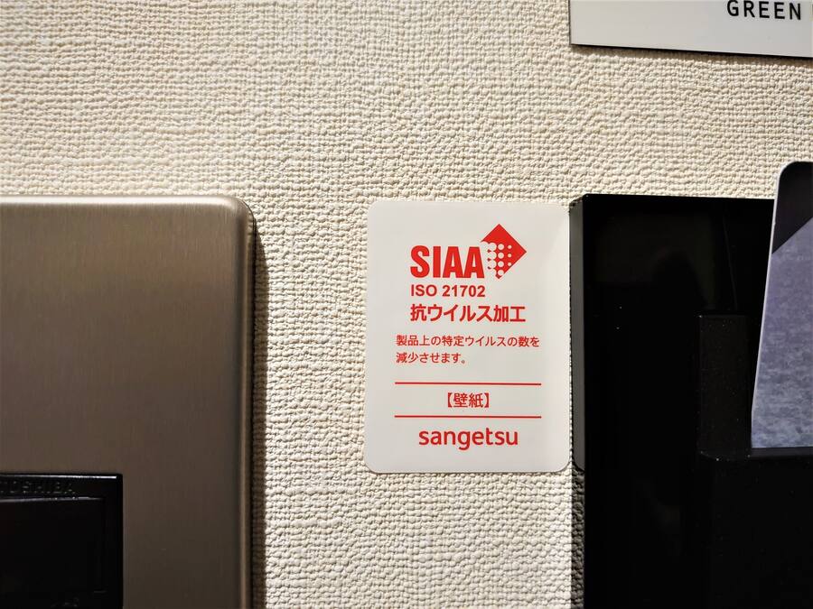A wall with a sign indicating a specific ISO standard for a product, a label with the brand name 'sangetsu,' and a section labeled 'GREEN.'