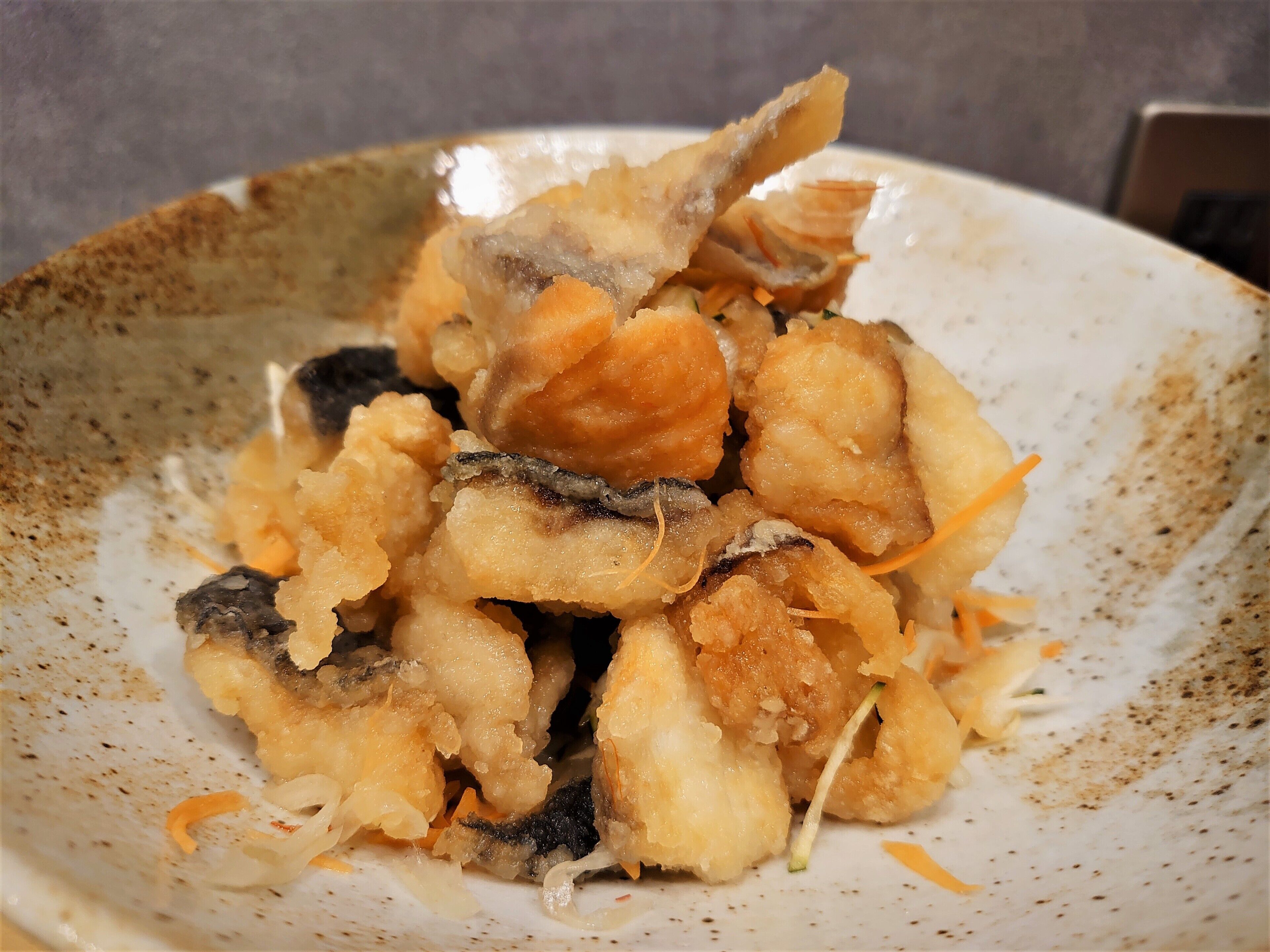 A plate of fried fish with vegetables.