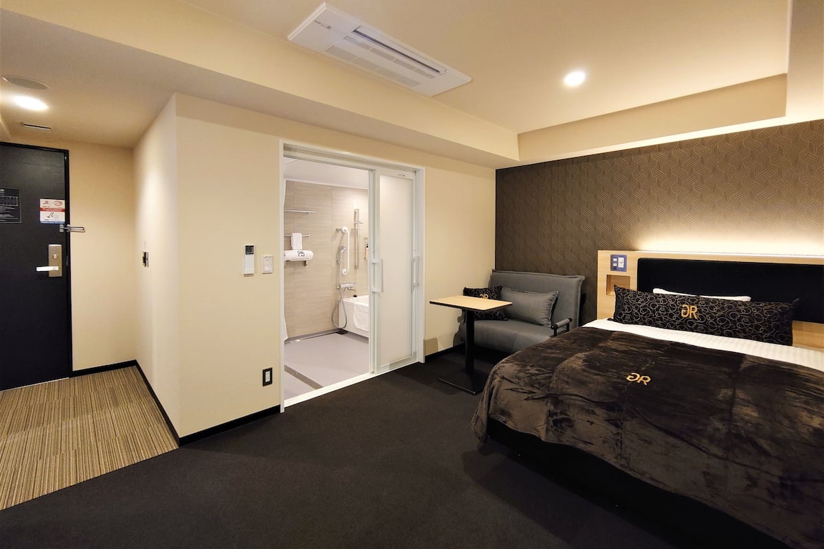 Een hotelkamer met een bed, een bureau, een stoel, een kledingkast en een badkamer.