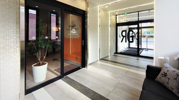 Un moderno vestíbulo de hotel con una recepción, un área de descanso y un acceso por puerta de vidrio.