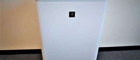 Un equipo de aire acondicionado blanco, con diseño acanalado y forma rectangular, con un panel de control en la parte superior y el nombre de la marca 'SHARP' en la parte inferior.