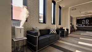 Un vestíbulo moderno con un sofá de cuero negro, un humidificador blanco y un mostrador de recepción.