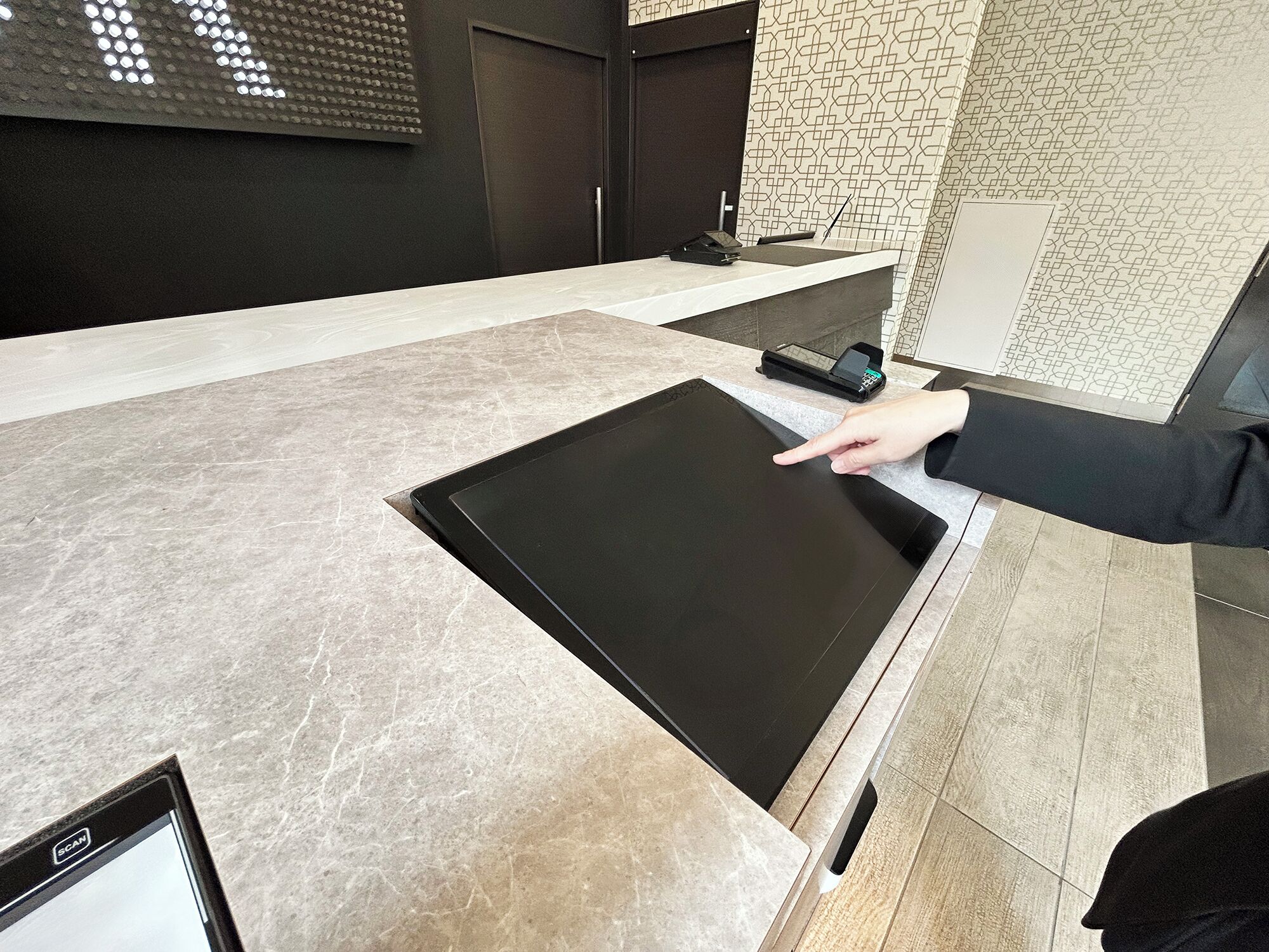 A modern reception desk with a flat-screen monitor, a digital keypad, and a small printer.