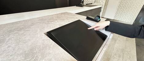 A modern reception desk with a flat-screen monitor, a digital keypad, and a small printer.