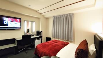 Habitación de hotel con cama, escritorio, silla, televisión y ventana con cortinas.