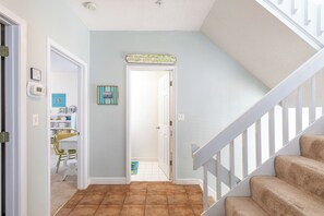 A hallway with a staircase, a door leading to another room, and a wall-mounted sign.