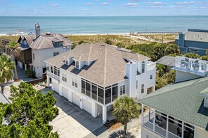 A coastal property with a large house featuring multiple decks and a view of the ocean.