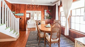 A dining area with a wooden table, chairs, and a patterned rug.