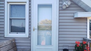 A front door with a glass panel, a bench, and a potted plant on the porch. - Tina's bungalow  (Manitowoc)