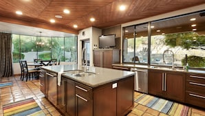 Una cocina moderna con una isla grande, electrodomésticos de acero inoxidable y vistas al exterior.