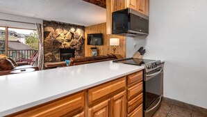 A modern kitchen with wooden cabinets, a built-in oven, and a stone accent wall. - Hike In/Out w/Unforgettable Views+ Hot Tub-W/D in Unit-Mini Arcade-Fireplace-Deck (Steamboat Springs)