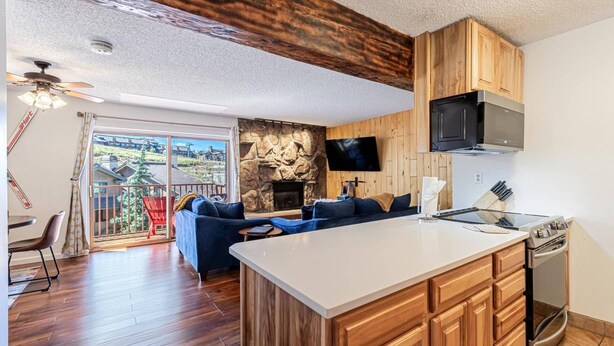 A modern kitchen with wooden cabinets, a stone accent wall, a built-in oven, and a large island. - Hike In/Out w/Unforgettable Views+ Hot Tub-W/D in Unit-Mini Arcade-Fireplace-Deck (Steamboat Springs)