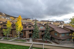 A residential building with multiple units, a fenced courtyard, and a hilly backdrop.