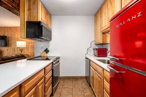 Eine Küche mit Holzausstattung, einem roten Kühlschrank, einer Mikrowelle, einem Herd und einem Spülbecken.