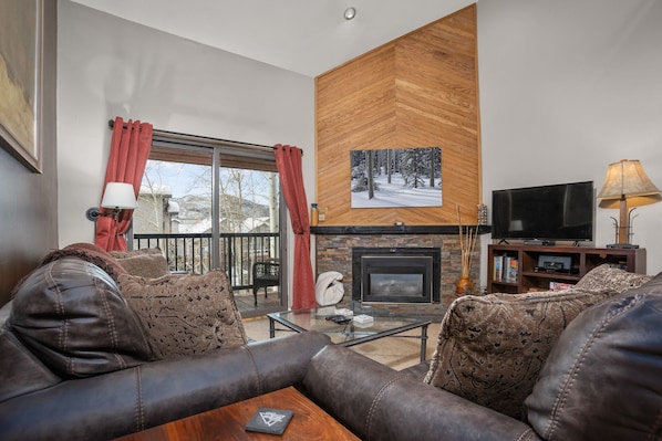 A living room with a fireplace, leather sofa, and a television.
