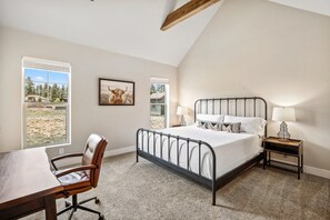 A bedroom with a bed, bedside tables, a desk, and a chair.