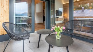 A modern interior with glass doors leading to a dining area, a small round table with chairs, and a vase with flowers. - Luxurious and beautiful lodge with fantastic view (Turracher Höhe)