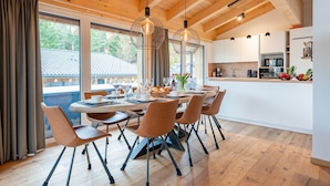 A modern kitchen with white cabinets, a wooden countertop, and a dining area with a table set for six. - Luxurious and beautiful lodge with fantastic view (Turracher Höhe)