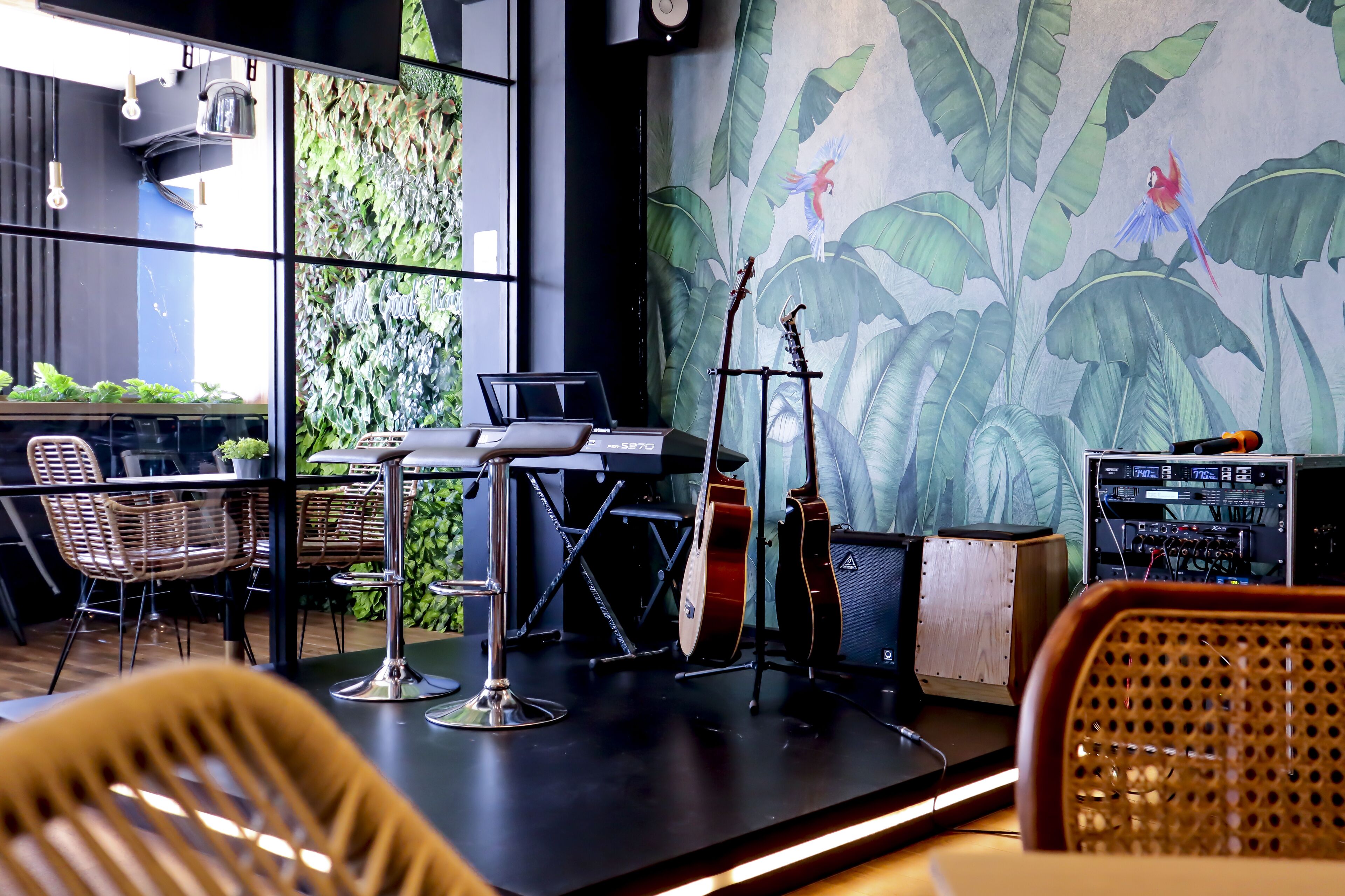 A modern interior with a stage, musical instruments, and a mural of tropical birds.