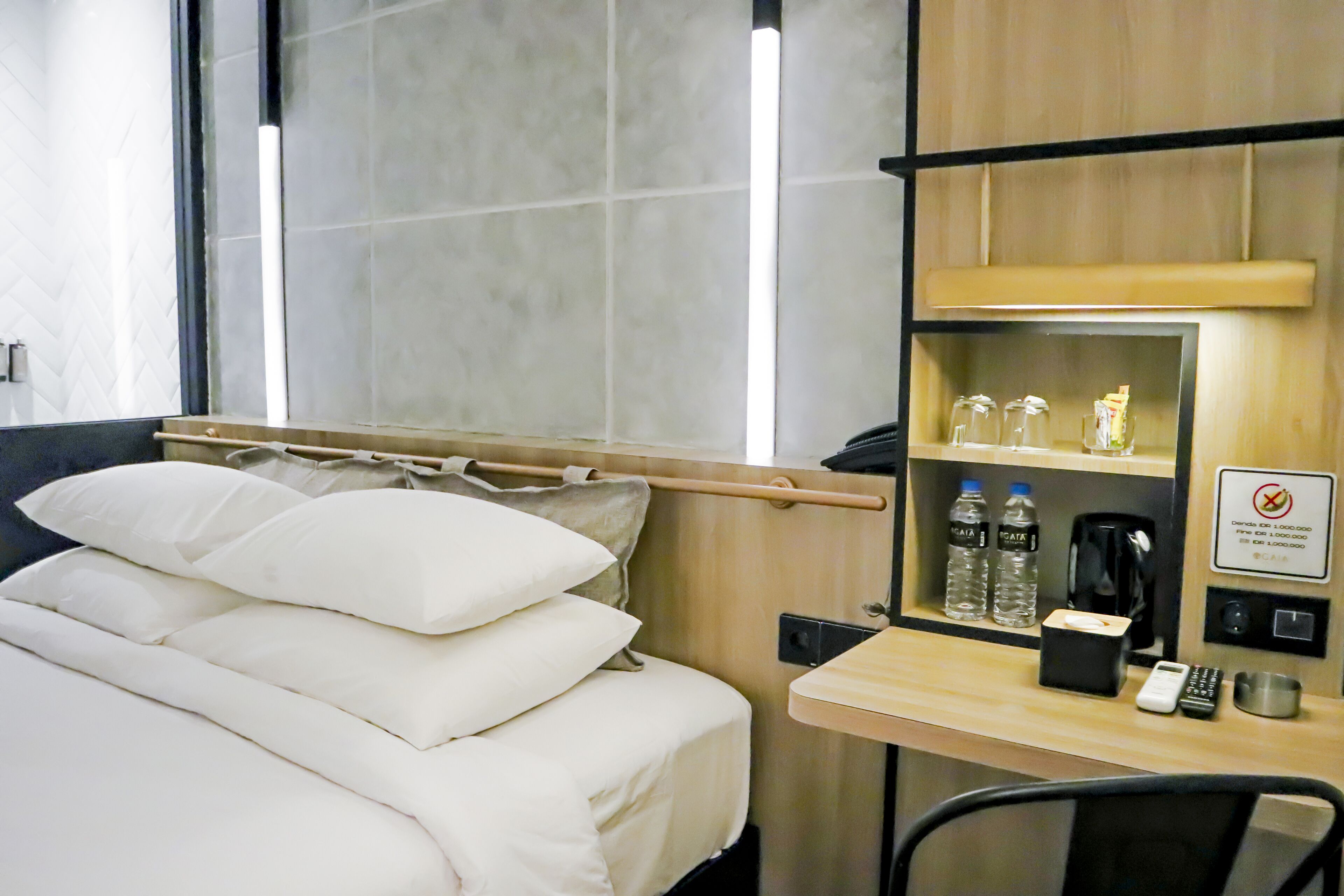 Une chambre d’hôtel équipée d’un lit, d’un bureau avec un téléphone, d’une machine à café et de bouteilles d’eau.