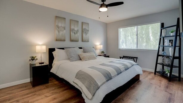 A bedroom with a bed, nightstands, a ceiling fan, artwork on the wall, a window, and a bookshelf. - Camelback Casa | Old Town Scottsdale | New Remodel (Scottsdale)