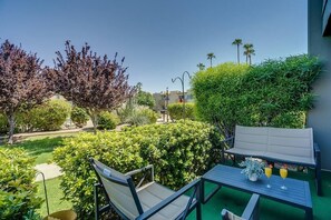 A balcony with outdoor furniture, including a table and two chairs, surrounded by lush greenery and a clear view of the surrounding area.