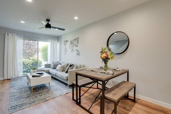 A modern living room with a sofa, coffee table, dining table, and bench.